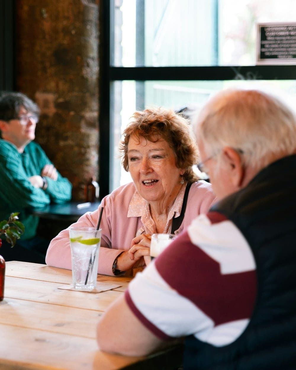 Two people talking across a cafe table, mid-conversation.