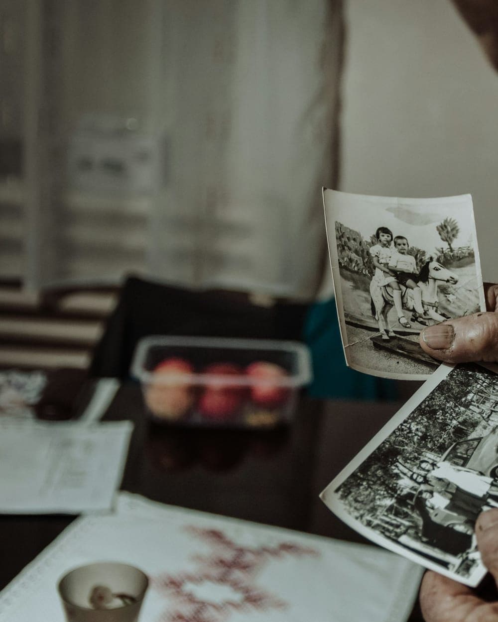 A pair of hands holding old black and white family photographs.